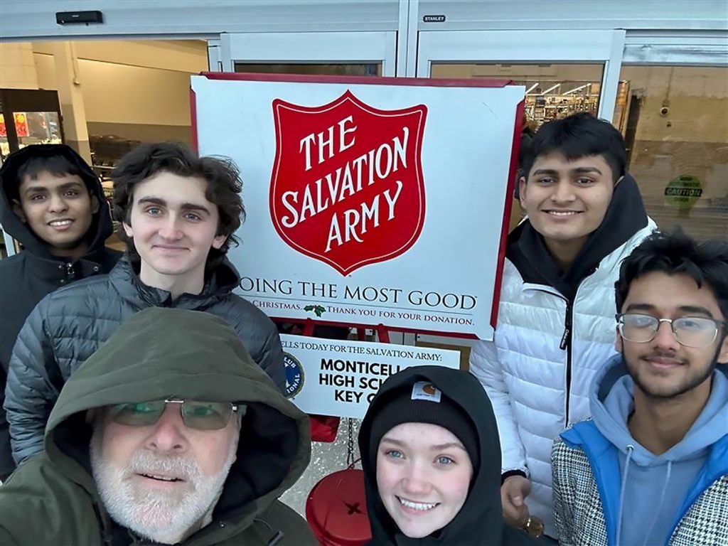 Students smiling in front of a "Salvation Army" sign.