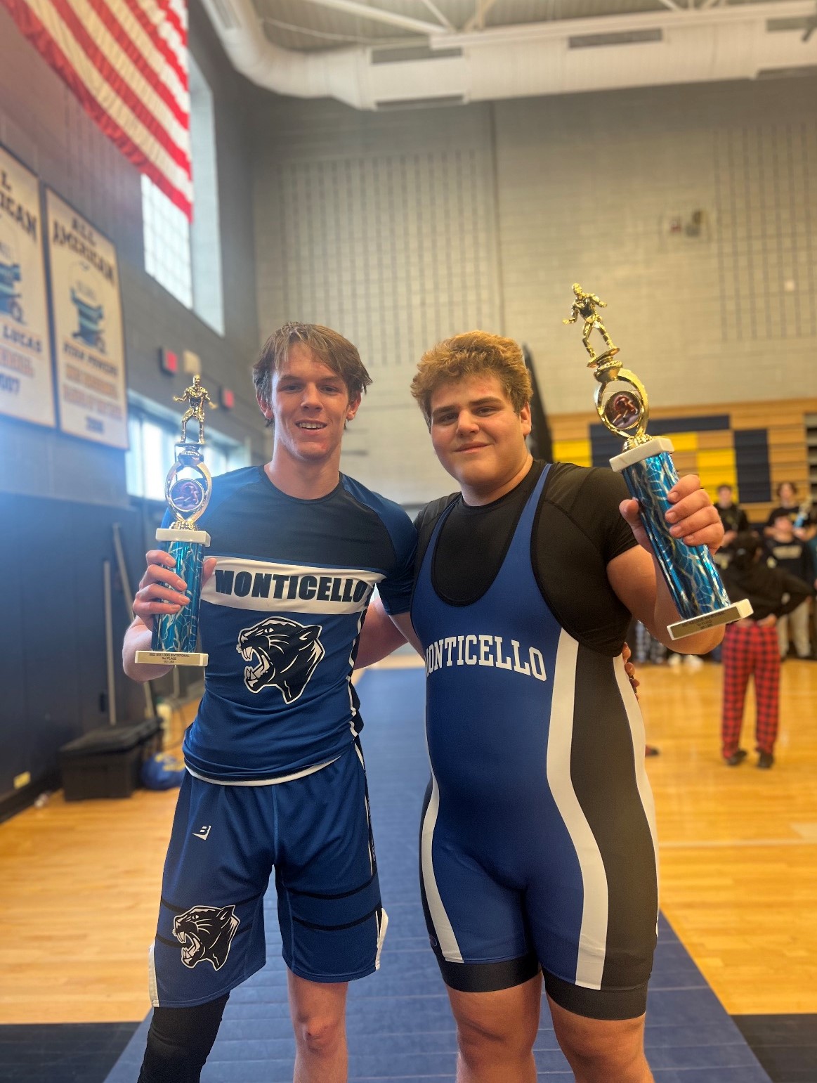 two students are posing in wrestling uniforms 