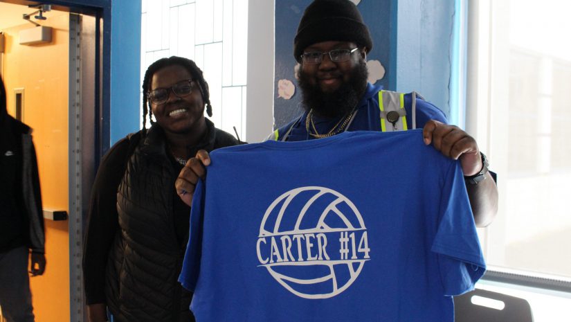 a student is posing with a security guard, who is holding up a tshirt.