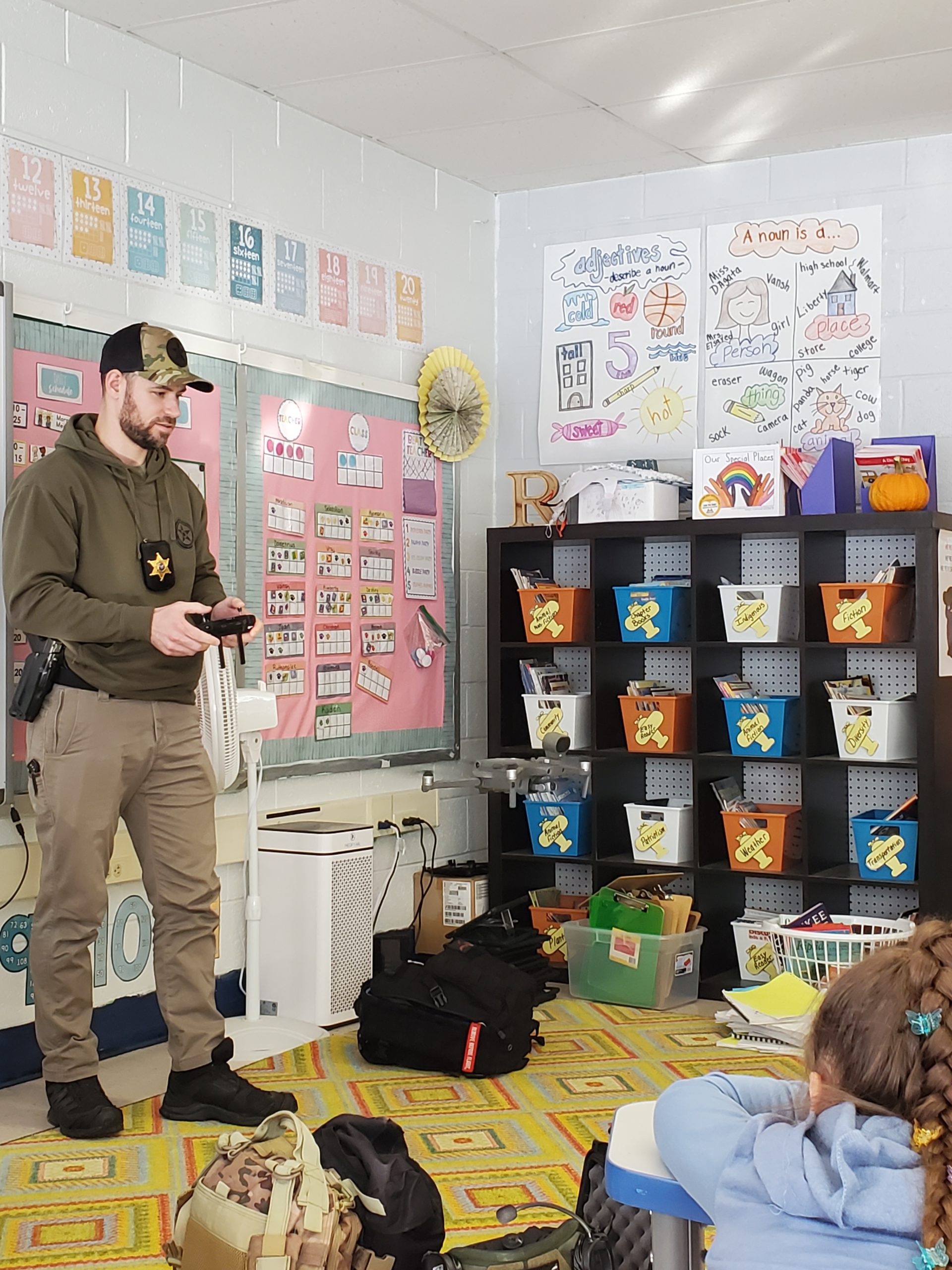an officer is flying a drone in front of a classroom of children