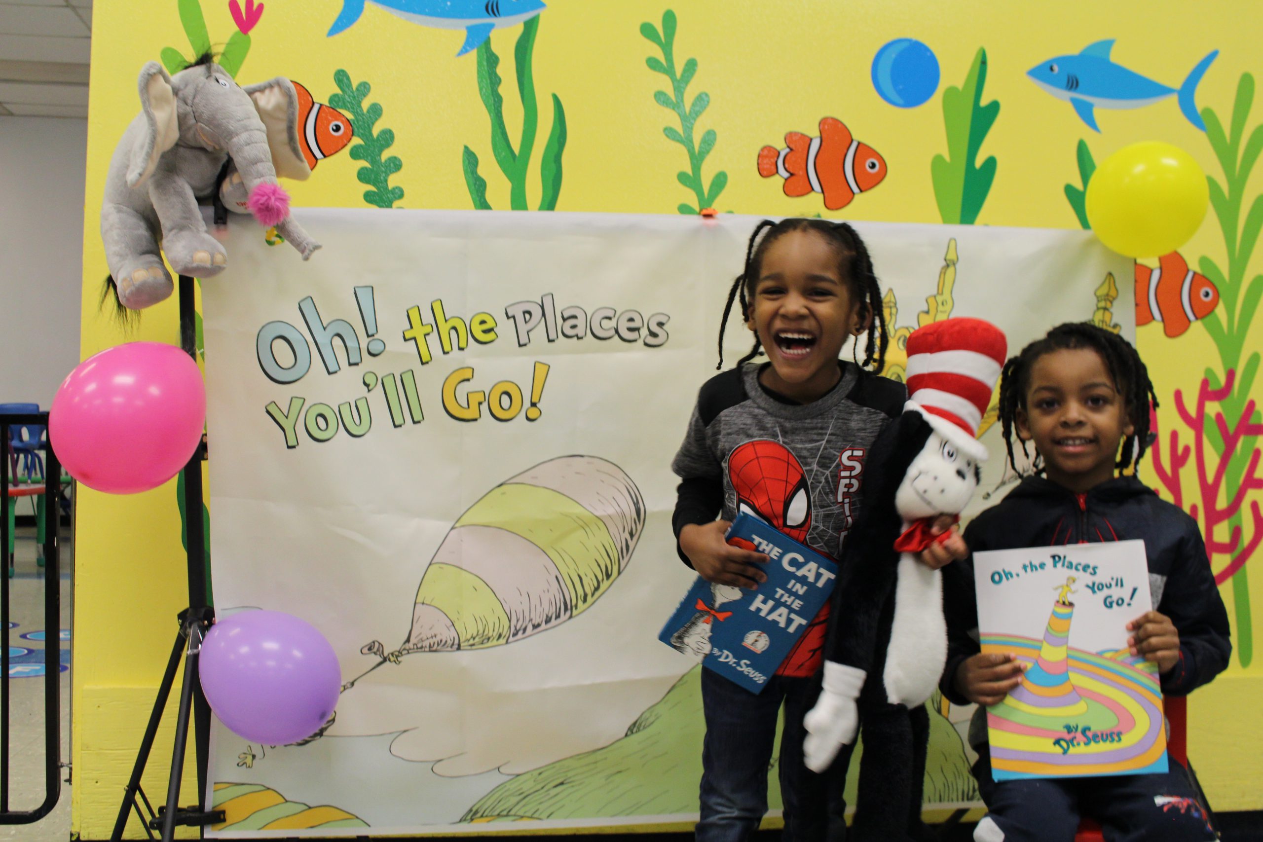 Two students are posing in front of a Seuss themed backdrop 