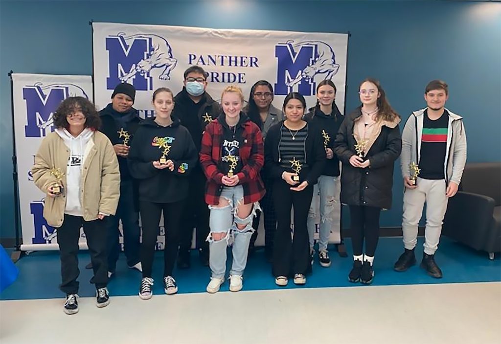 Students holding trophies for a group photo.