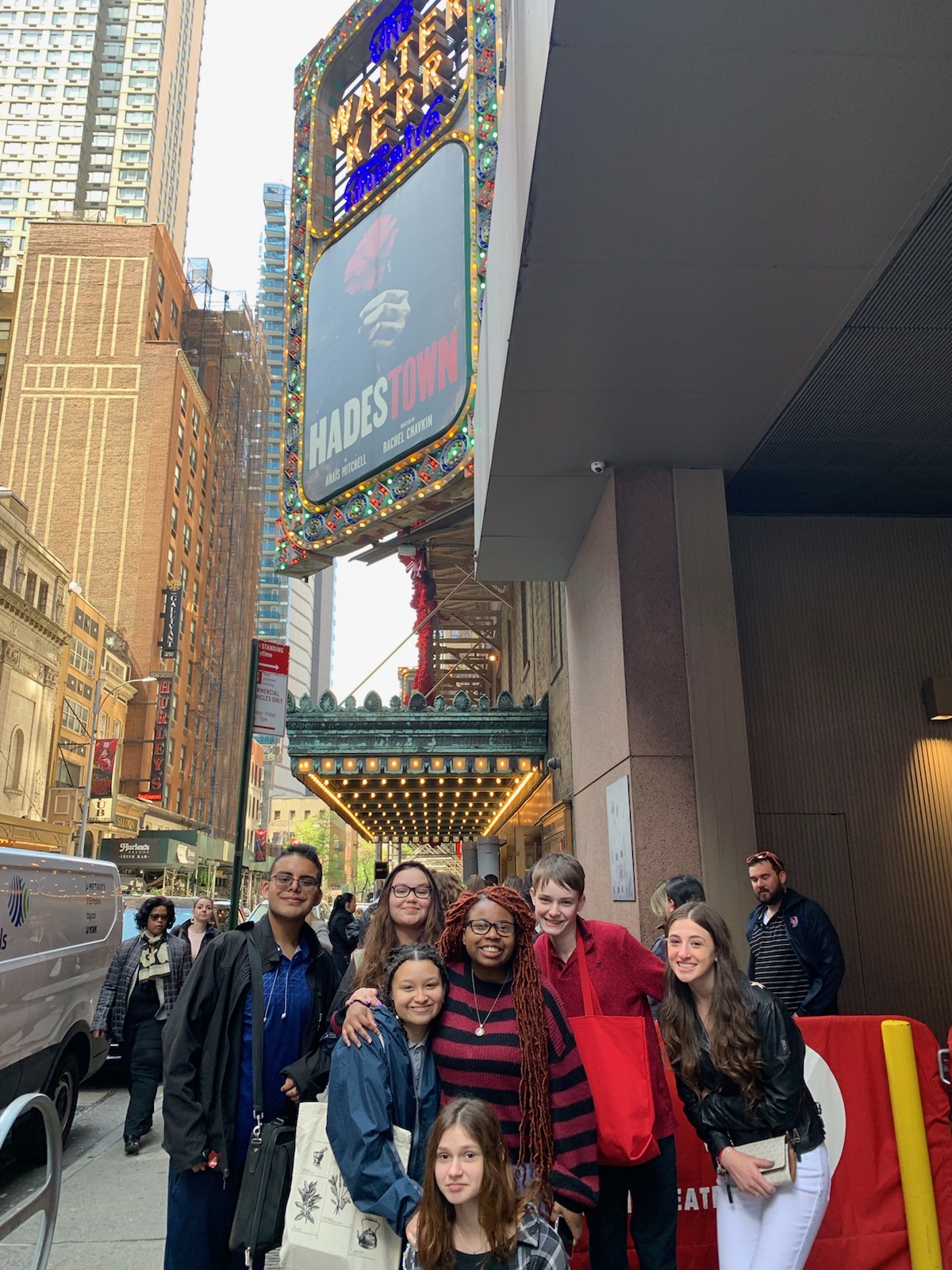 a group of students is posing outside of the Hadestown theater 