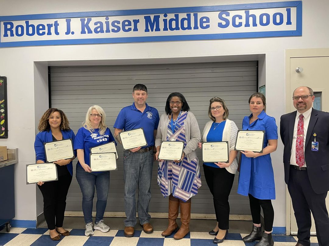 members of the board of education are posing and holding certificates 