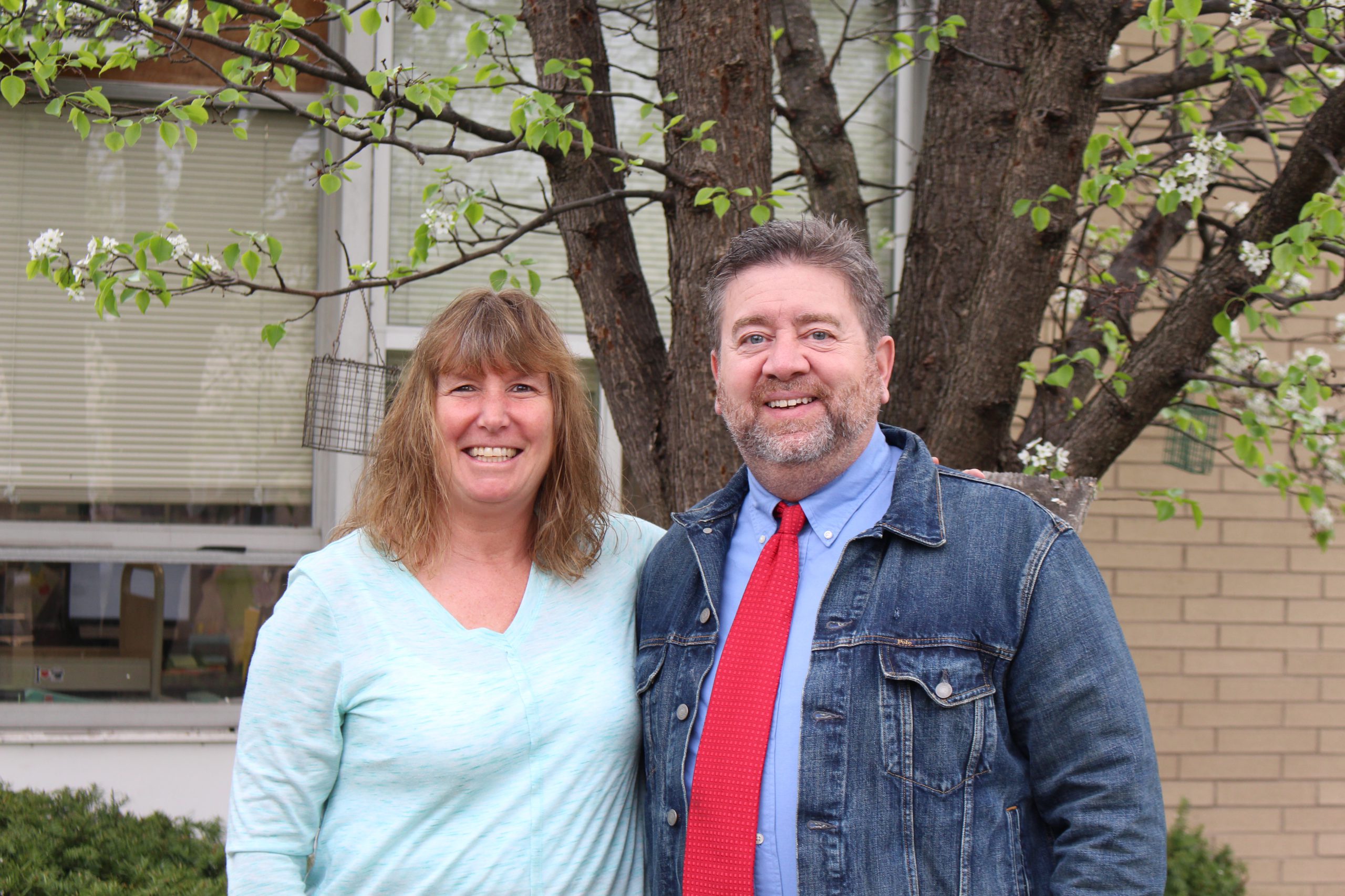 Ann Marie Kurthy and Bill Frandino are smiling next to a tree and posing 