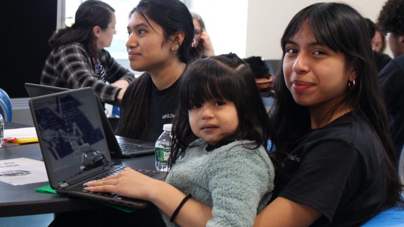 a girl is holding a toddler on her lap while typing on a computer