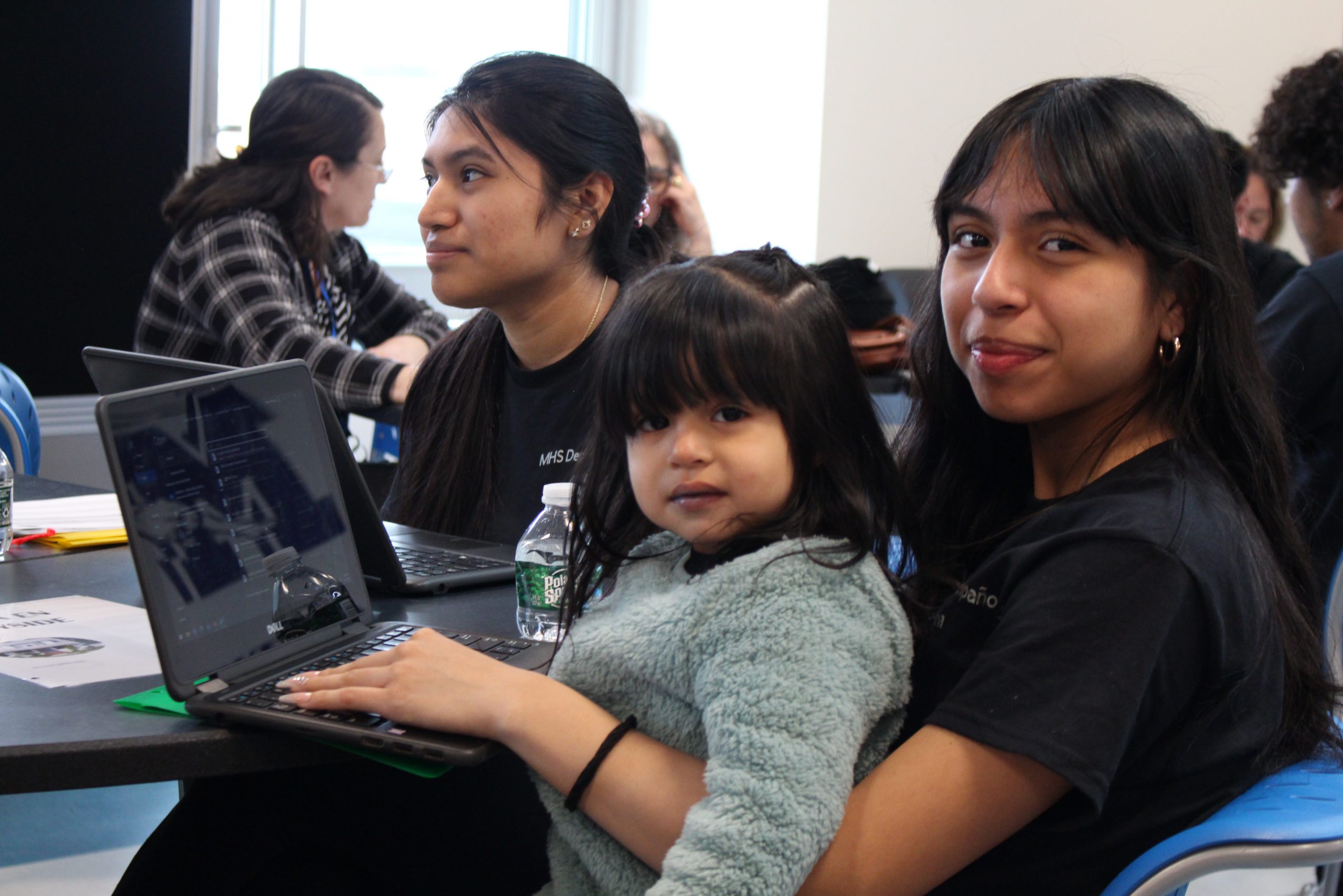 a girl is holding a toddler on her lap while typing on a computer 