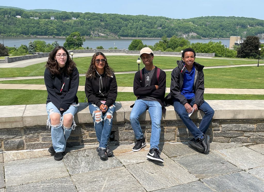 Four students sitting on a ledge outside.