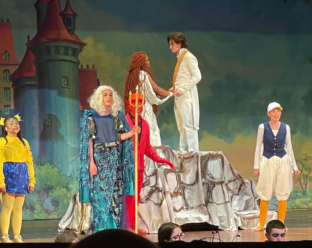 Students dressed as characters from the The Little Mermaid on stage.