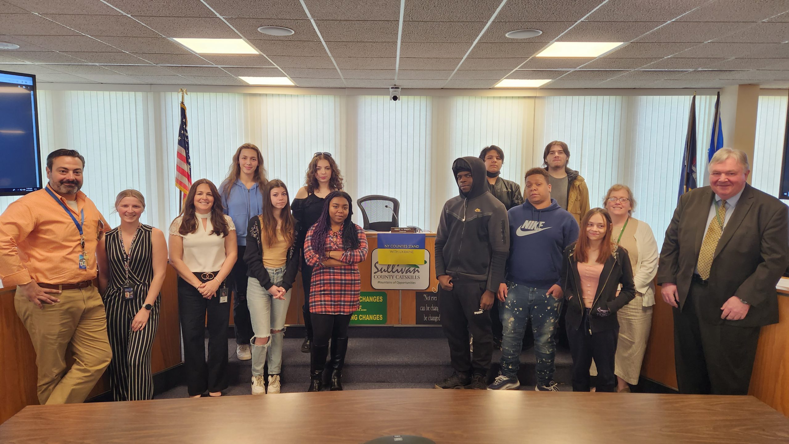 a group of students are posing in a legislative board room 