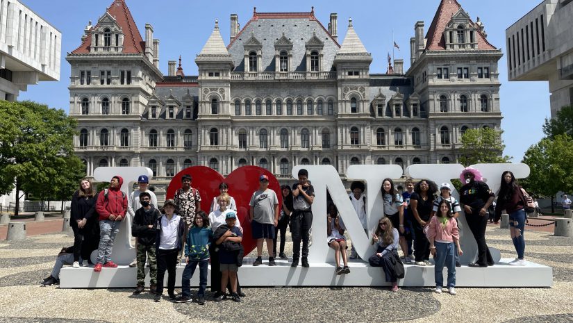 a group of students is posing outside of the New York State capitol building