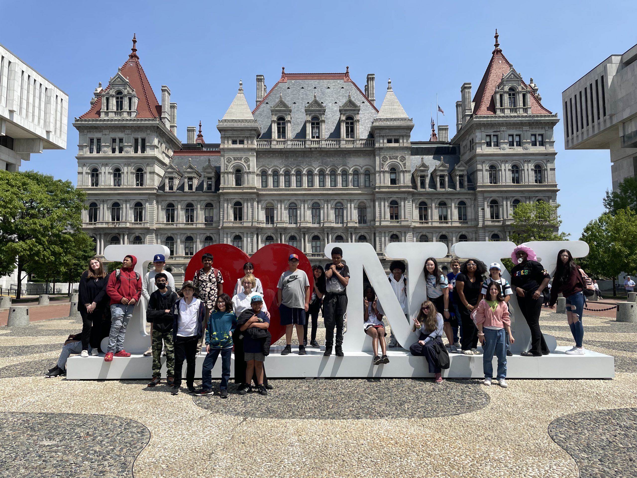 a group of students is posing outside of the New York State capitol building 