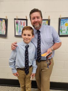 Kyle Roberts is posing with principal Bill Frandino. They are wearing matching outfits. 