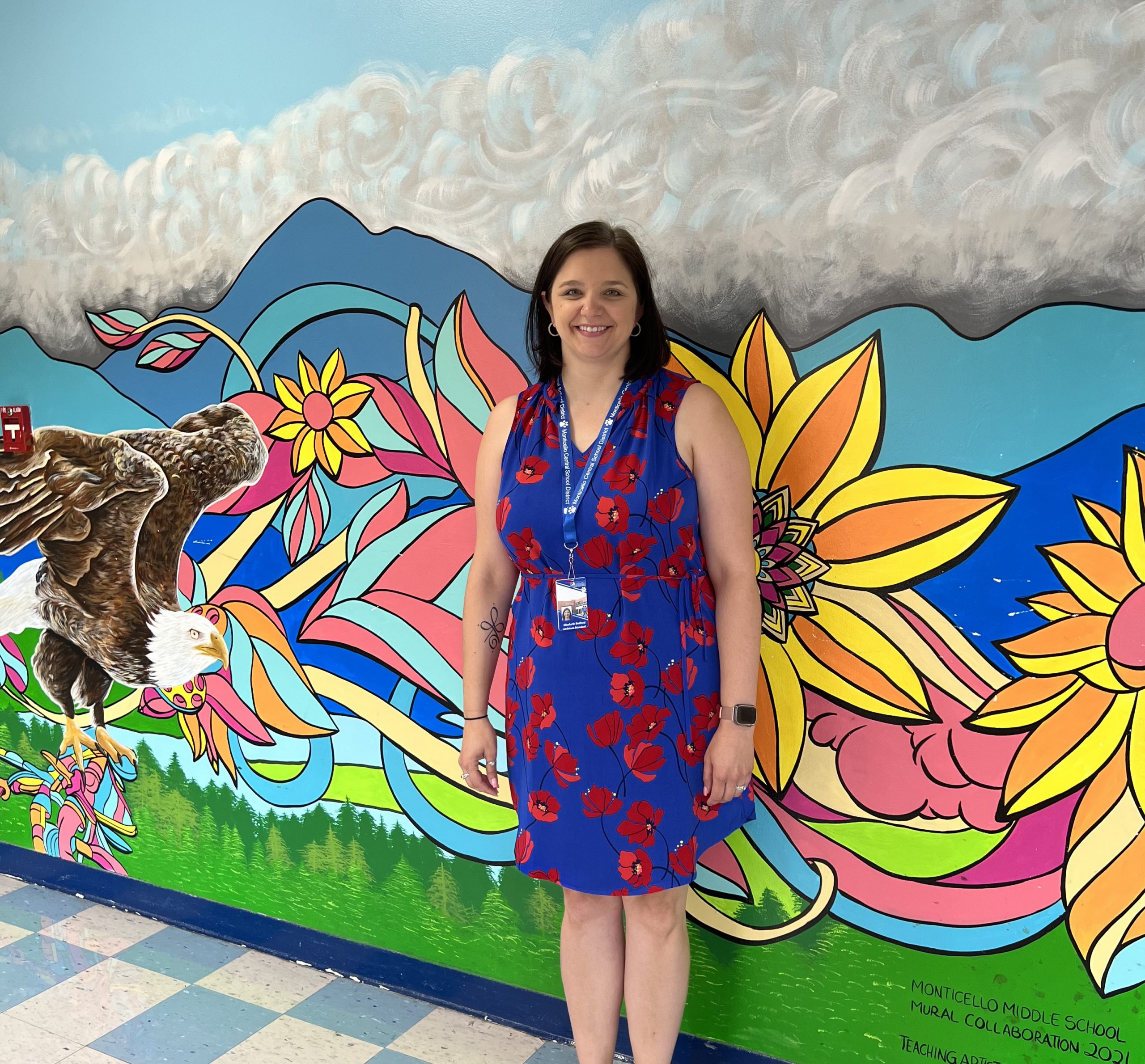 Elizabeth Bedford is posing in front of a mural at the Robert J. Kaiser Middle School