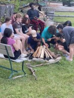 Students sit around a campfire