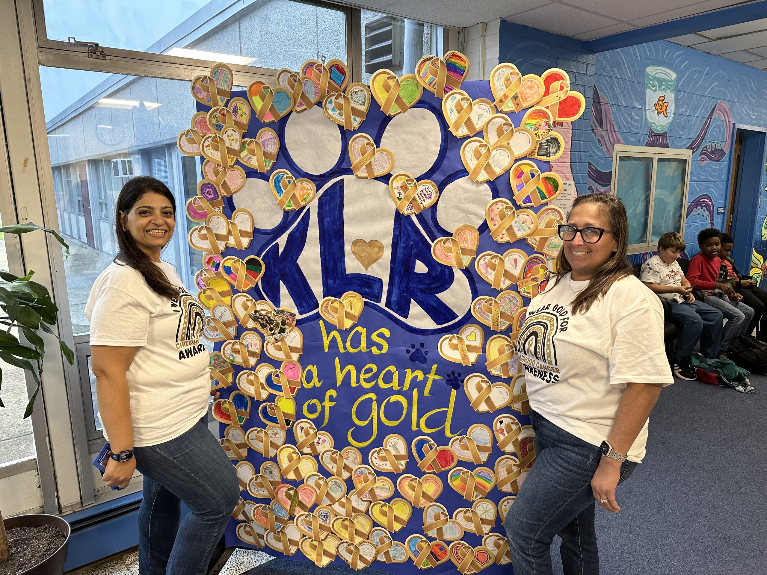 Two staff members stand near a display of gold hearts 