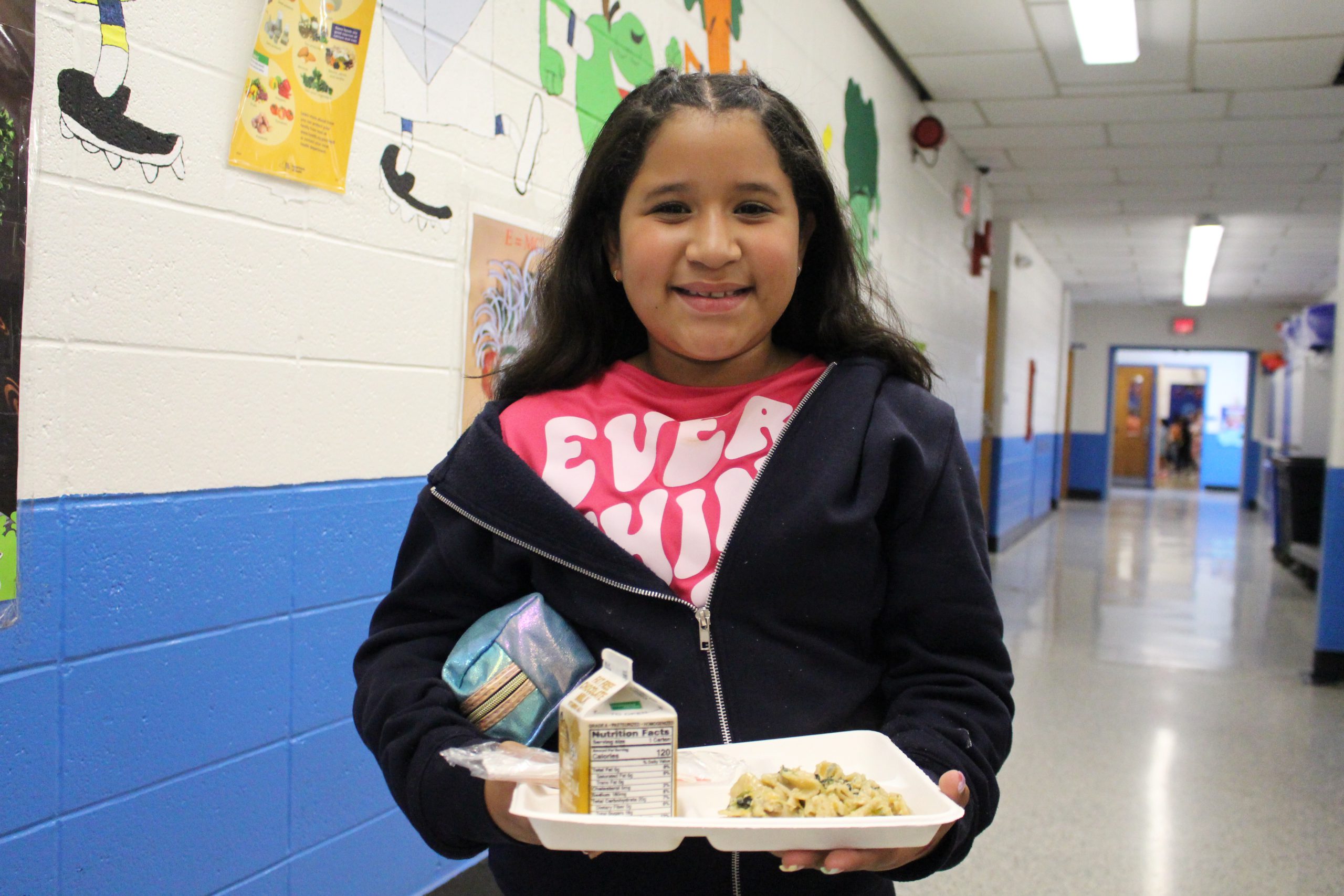 a young girl is holding a tray of food