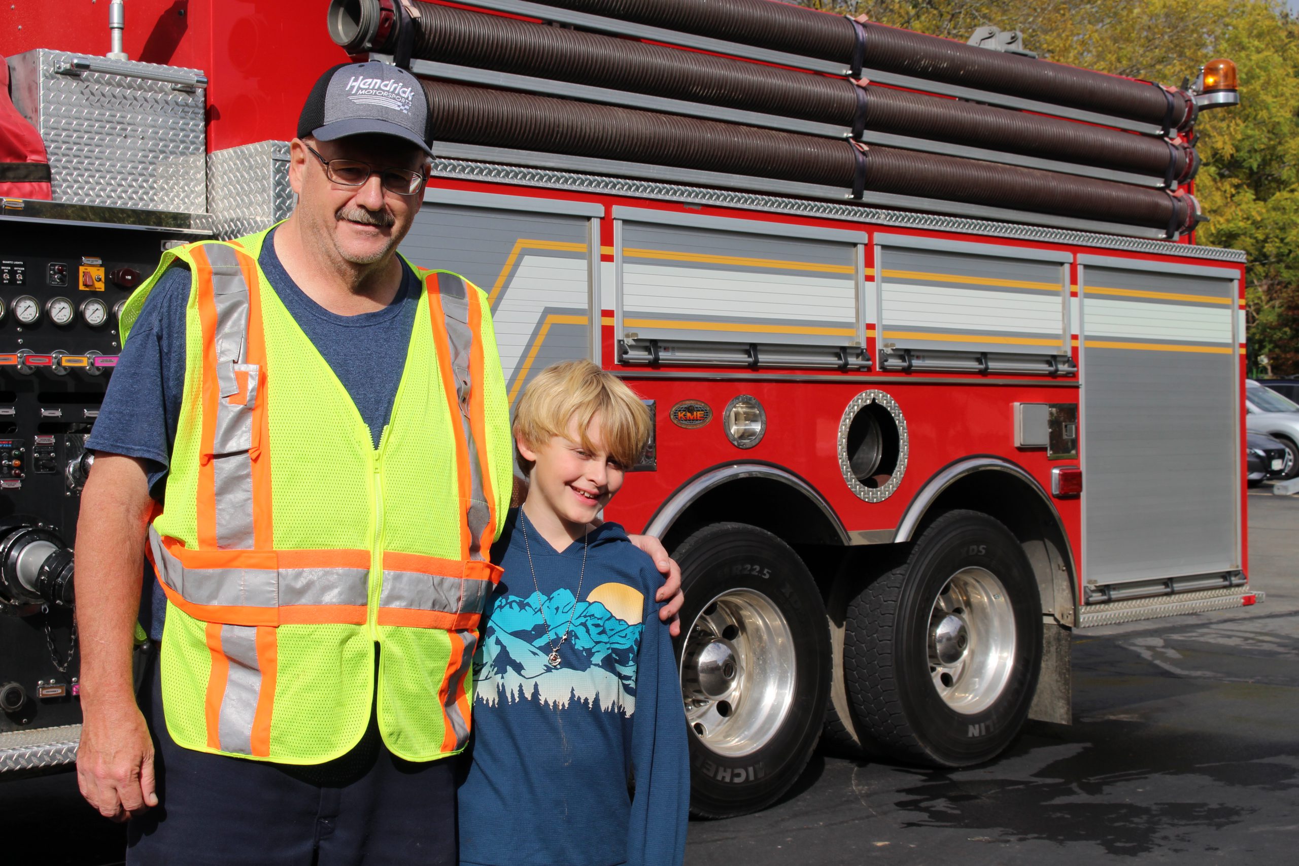 a firefighter is posing with a student near the truck