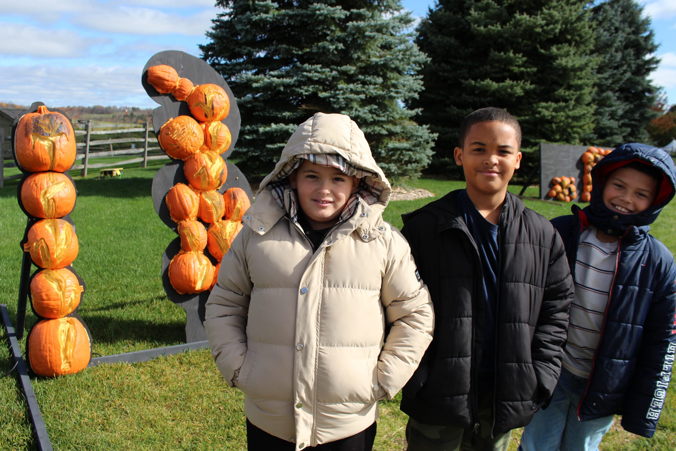 three male students are standing in front of a pumpkin art display 