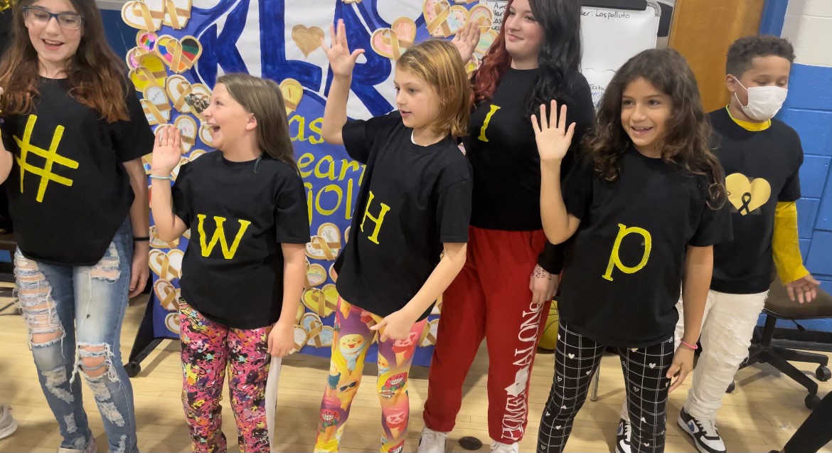 students are dancing at the front of the gym