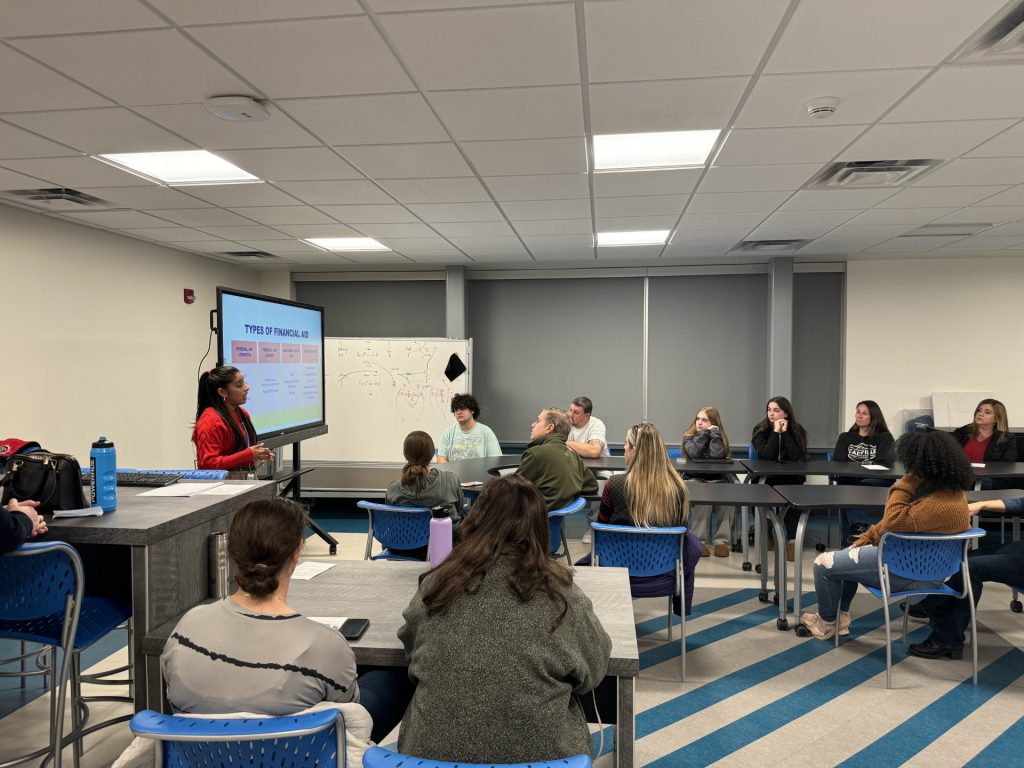 A woman is at a podium addressing the class. 