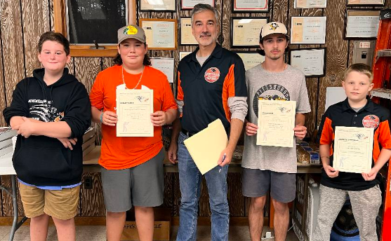 a group of students are holding certificates and posing with their coach. 