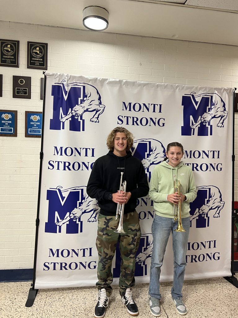 two students are posing and holding trumpets 