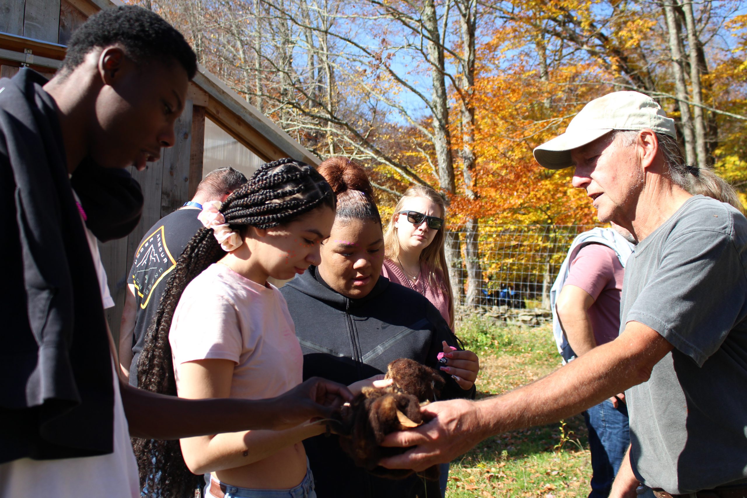 a farmer is extending his hand out to two students