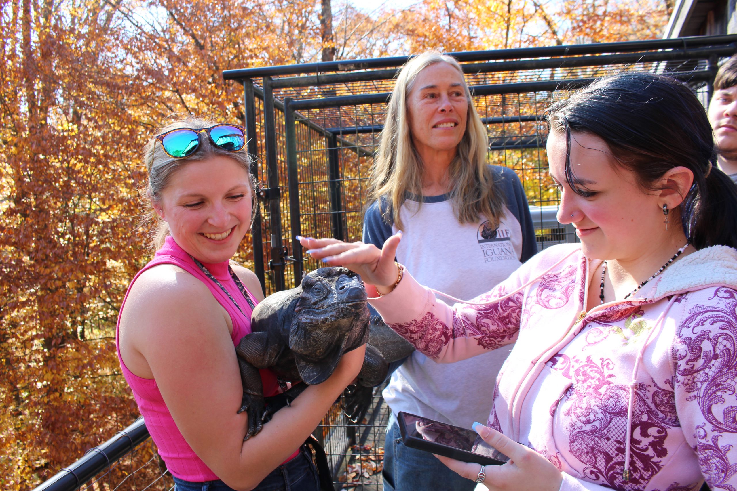 a teacher holds an iguana as a student pets it