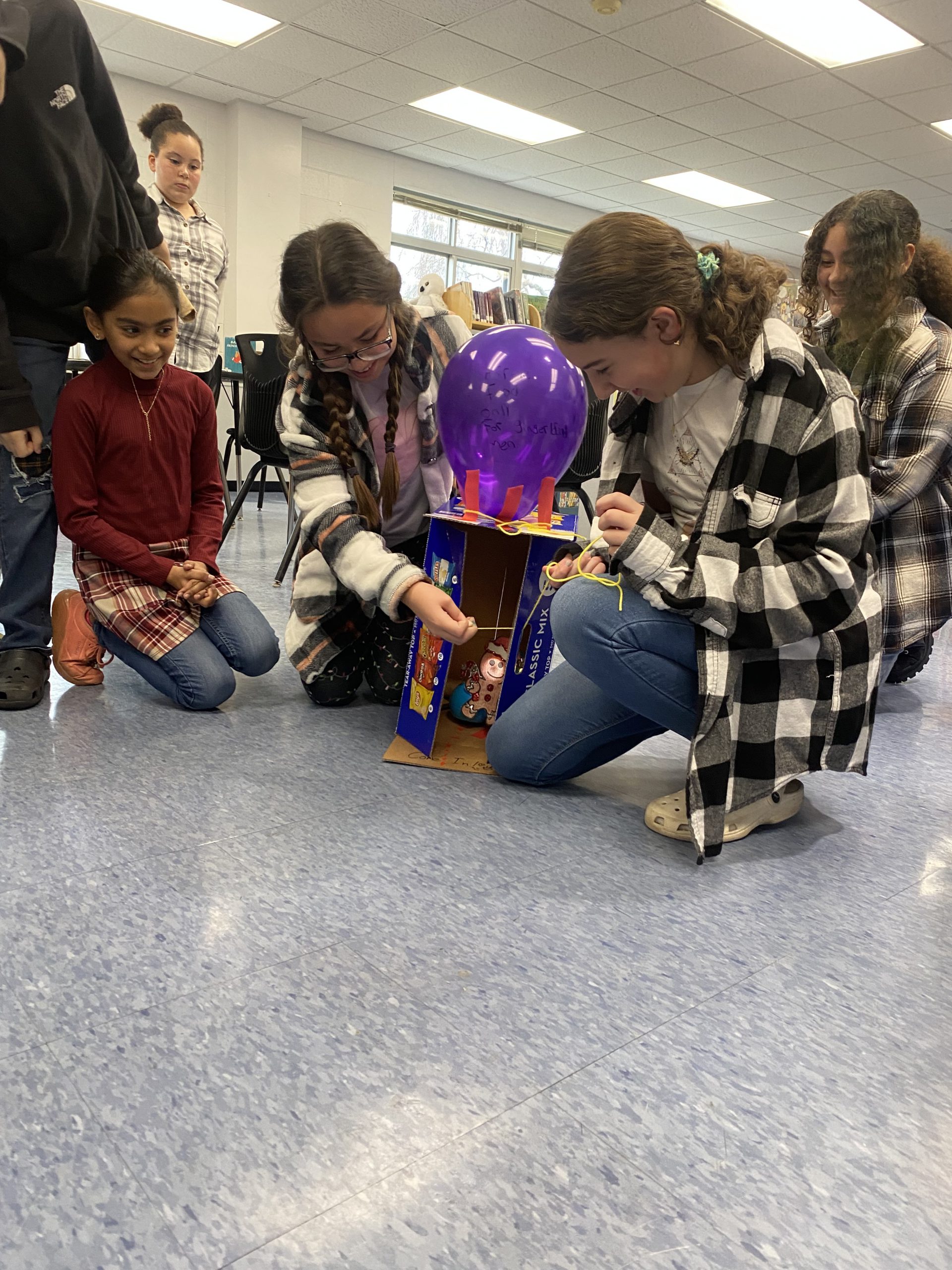 students are on the floor working to build a trap. 