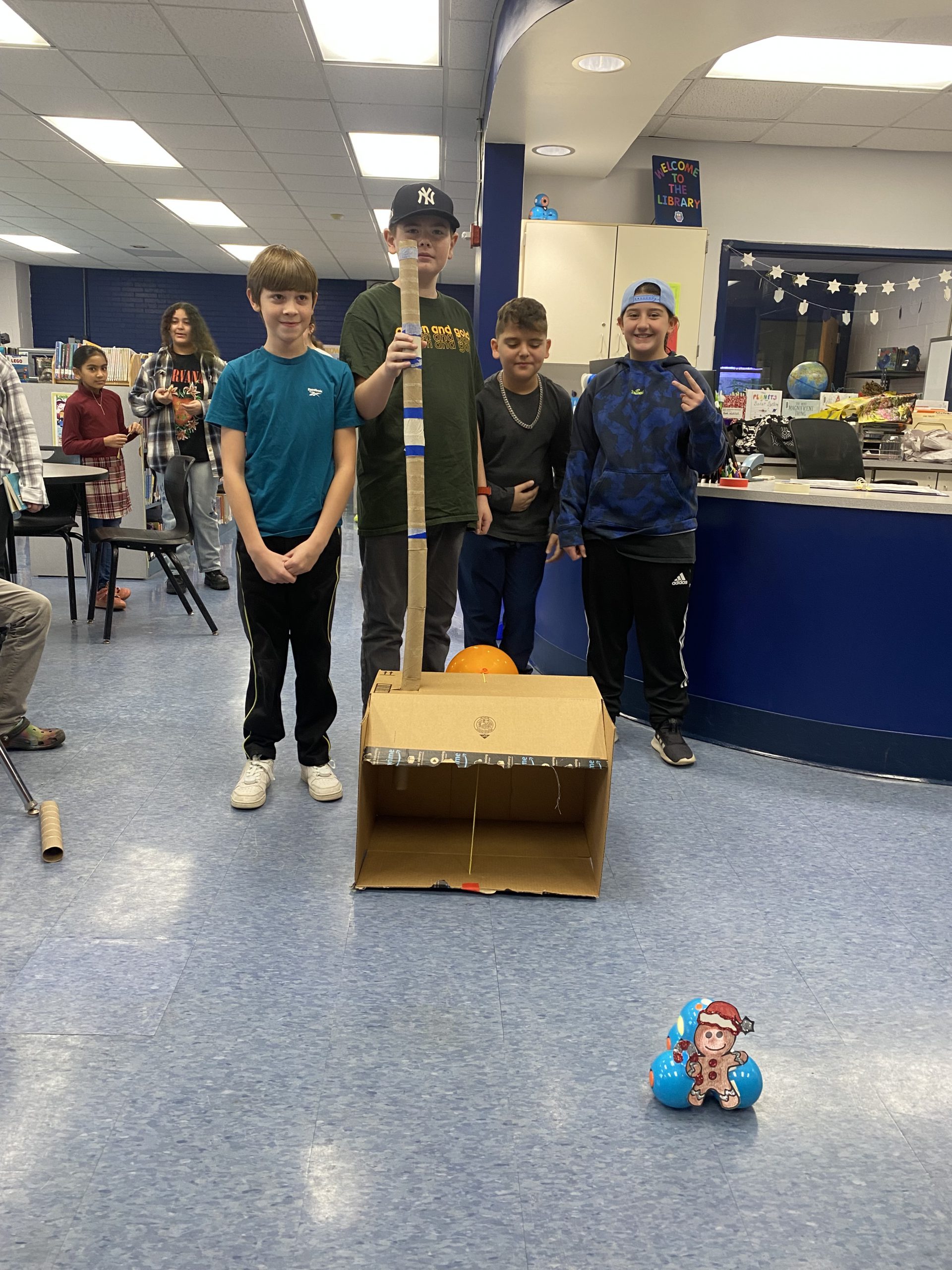 students pose around a box they made 