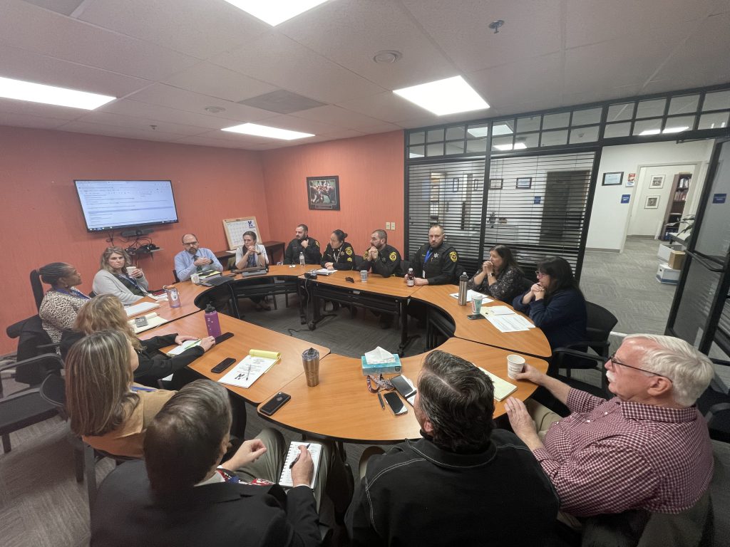 administrators and law enforcment members are seated around a table 