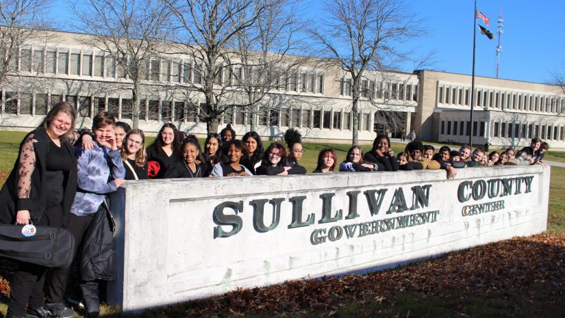 a group of students is posing behind the sullivan county government center sign