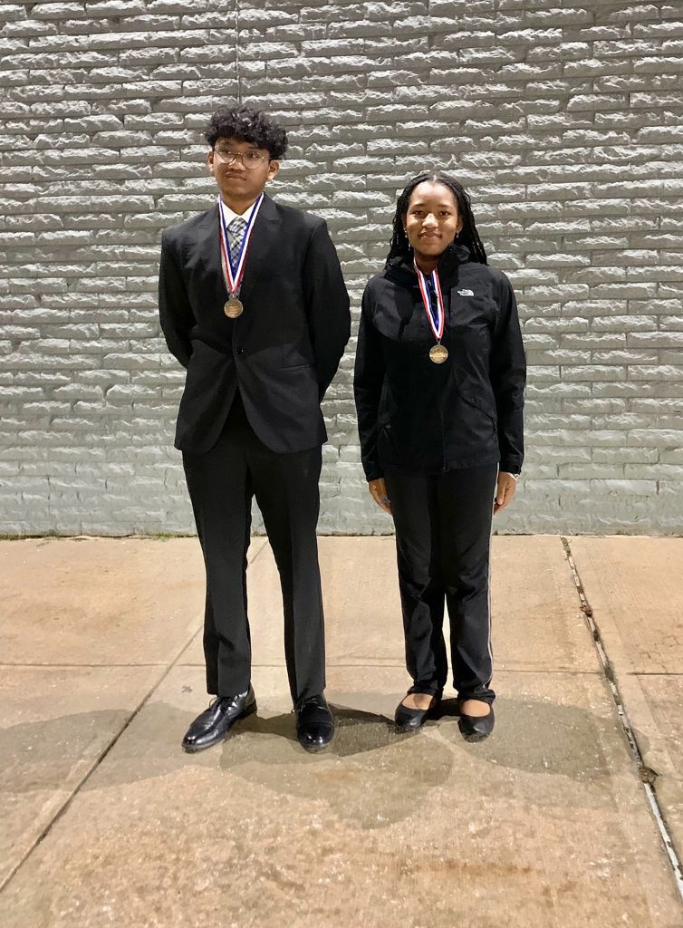 Two students wearing medals and smiling.