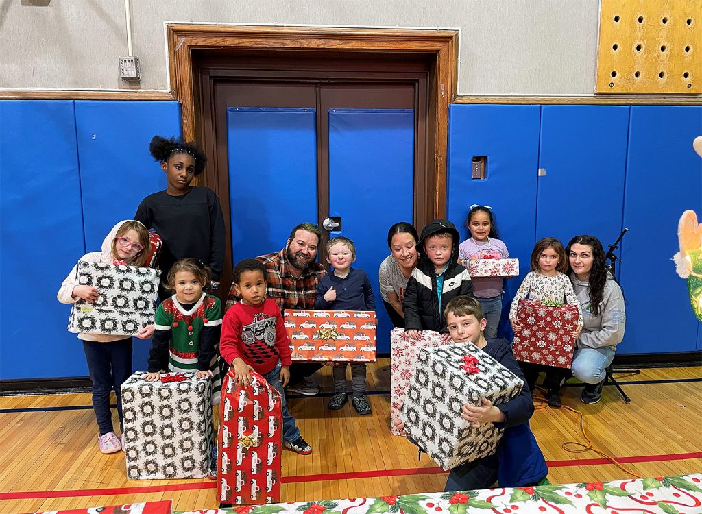 Parents and students smiling for a photo together while holding gifts.