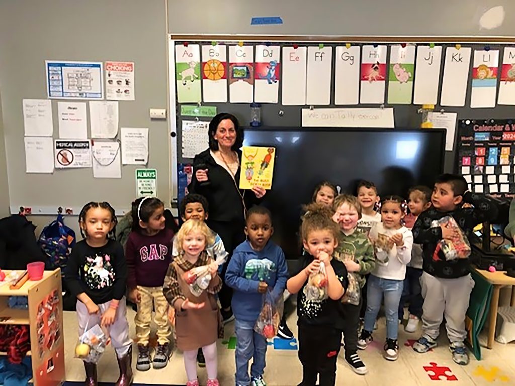 Teacher standing with preschool students in classroom for photo.