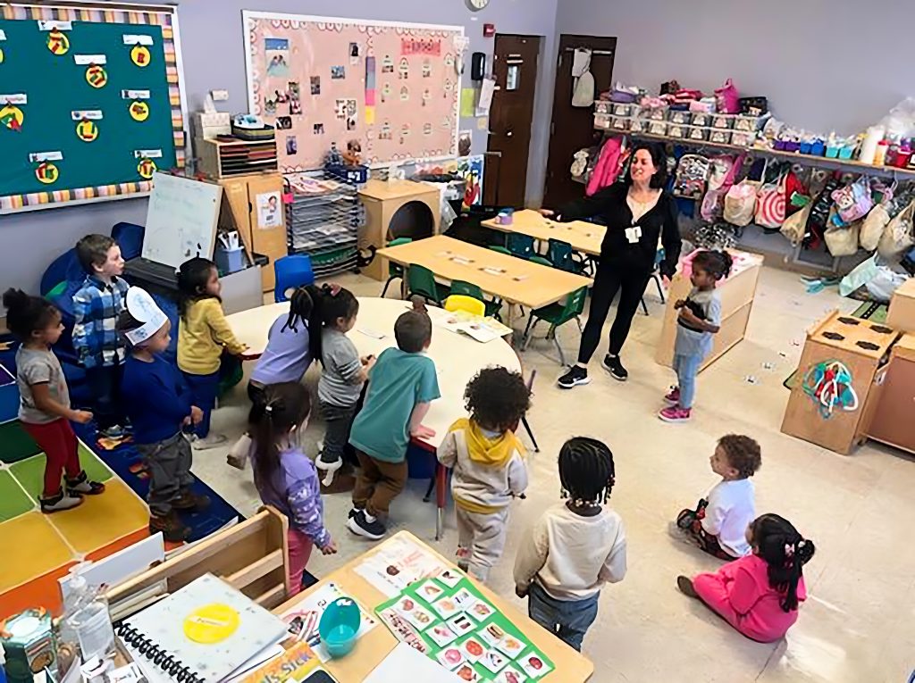 Teacher showing preschool students how to do an exercise.