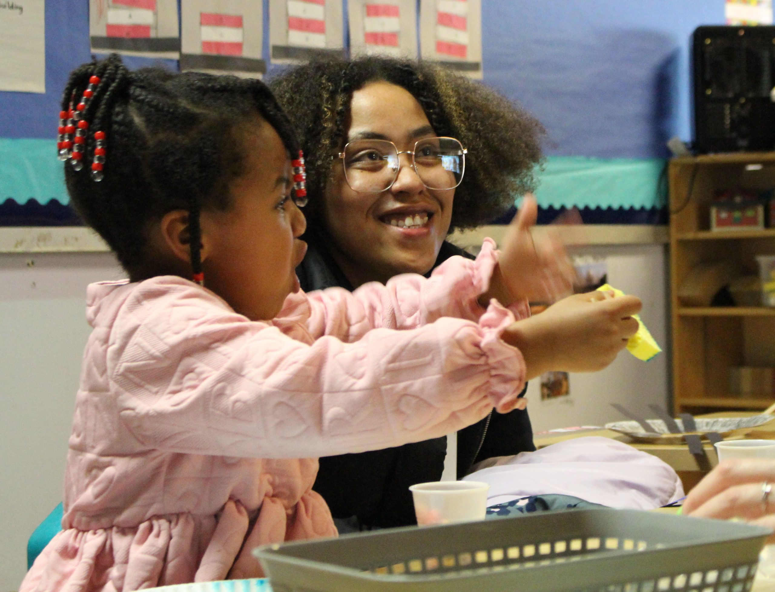 a mother and child are working on an activity at a table. 