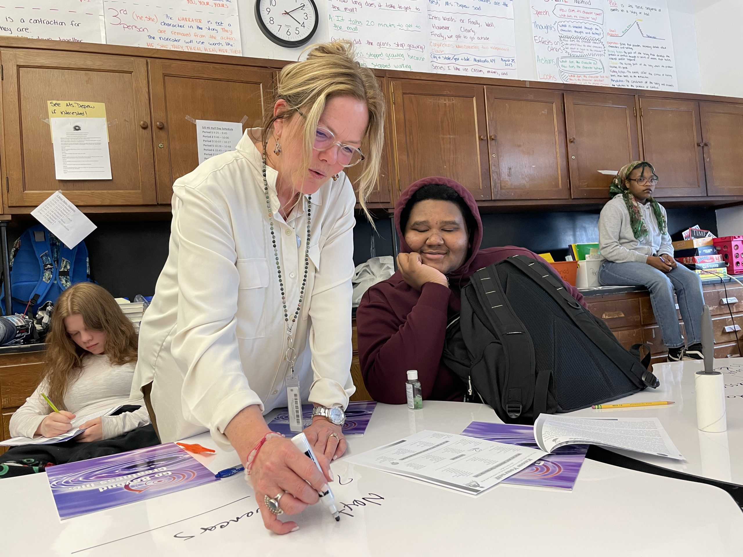 a teacher is writing notes as a student looks on