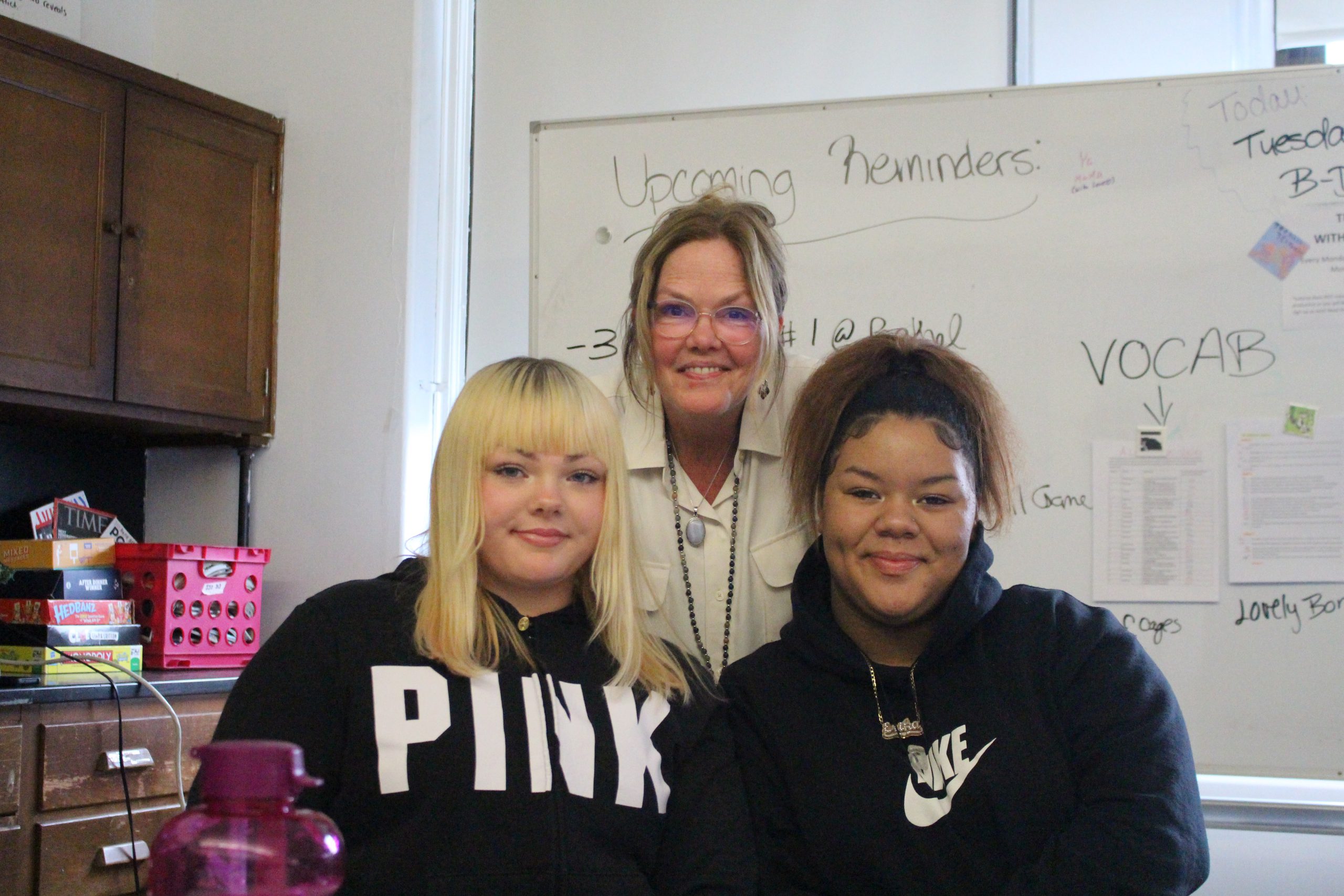 a teacher is posing with three students 