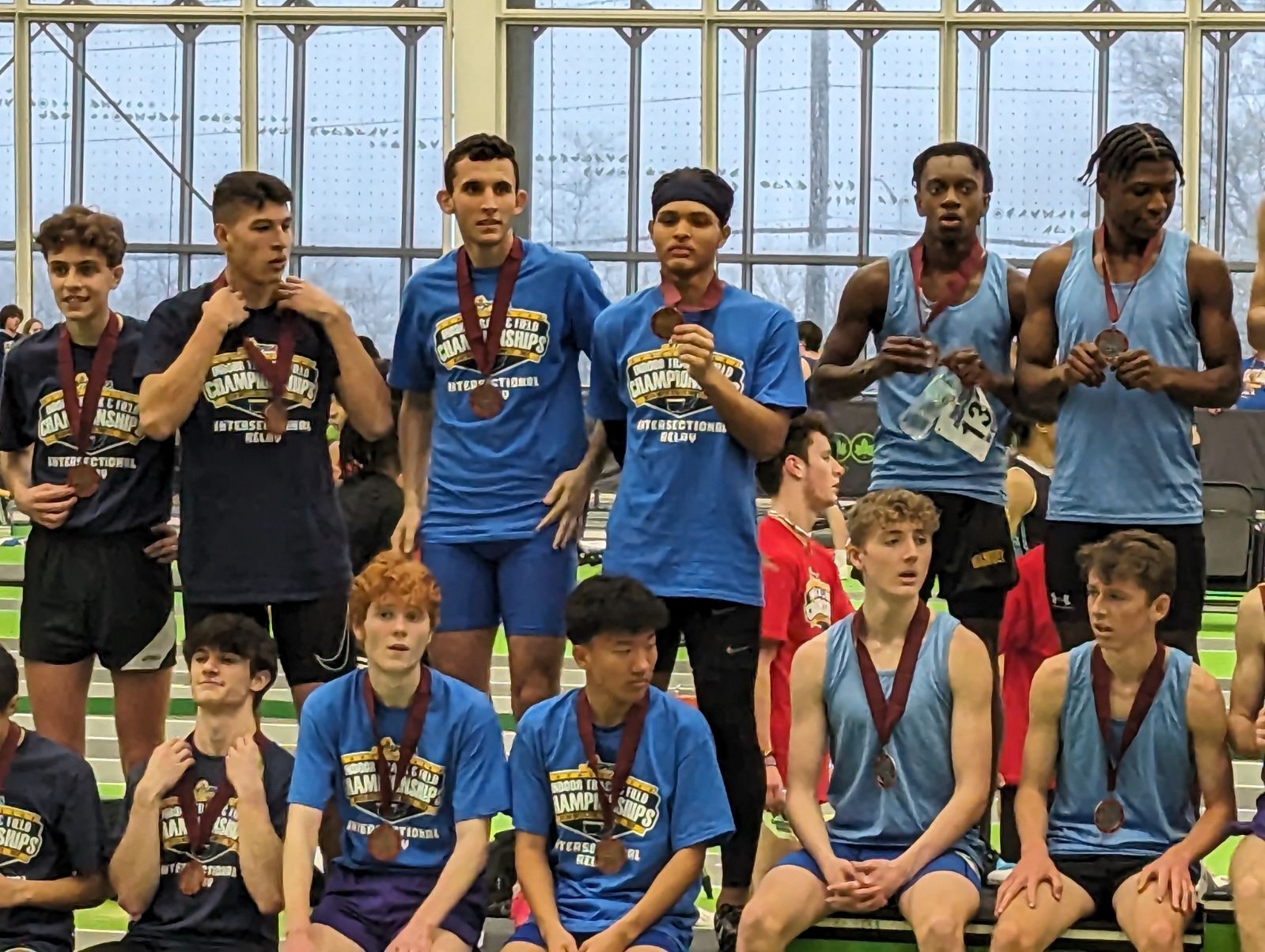 Tyrese Shaw, flanked by his team, is standing with a medal