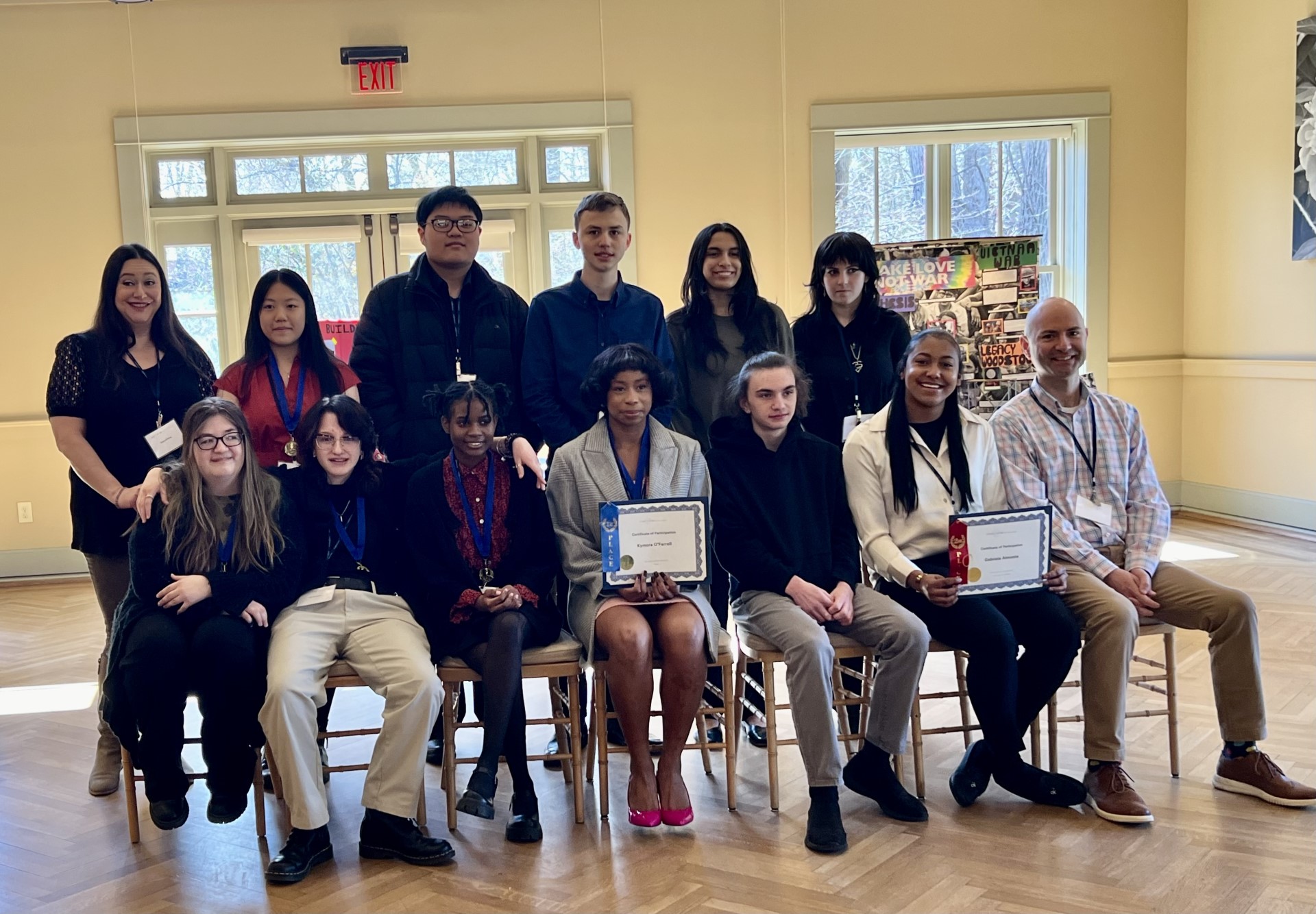 a group of students are seated and holding up their certificates/