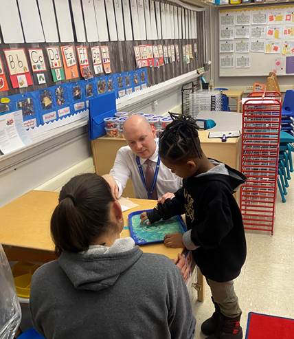 director ketith petzinger assists a student with a craft 