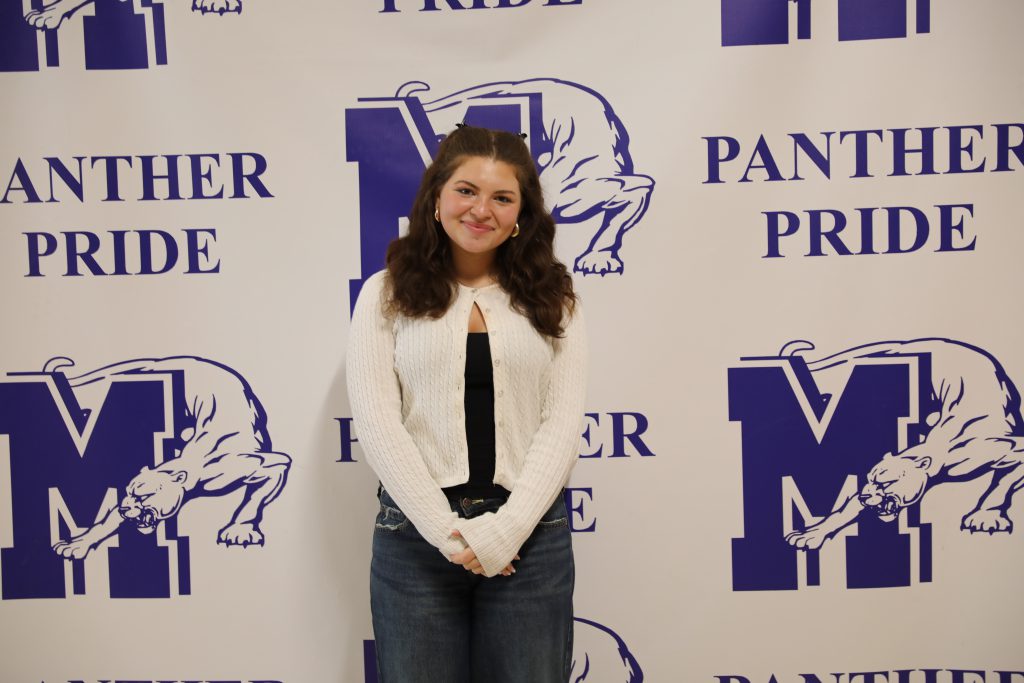 Lyndsey Kaplan smiles in front of a Monticello Panther Pride backdrop