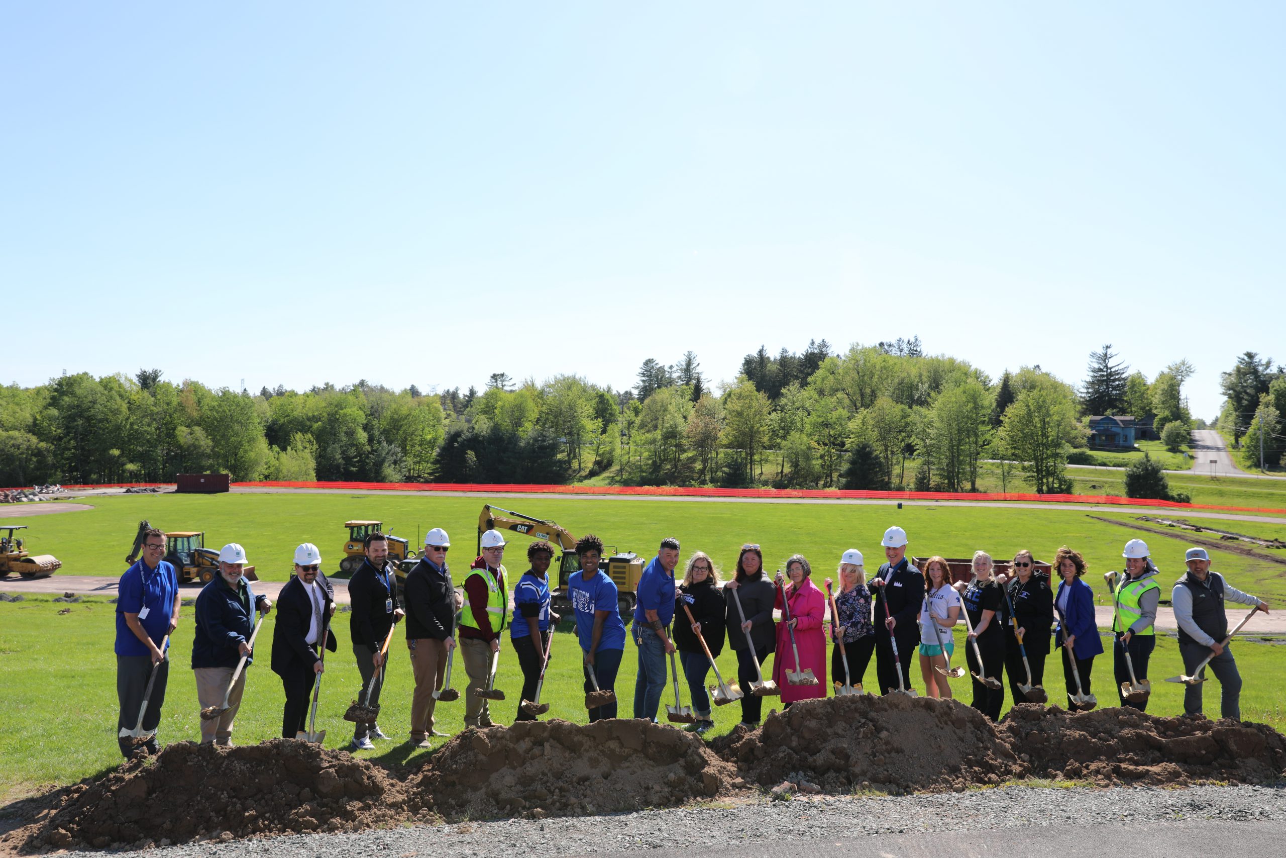 staff are standing with celebratory shovels in front of a field 