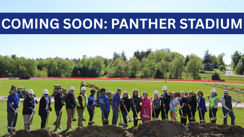 a large group of people are posing with shovels. In the background, the Monticello athletic fields are under construction