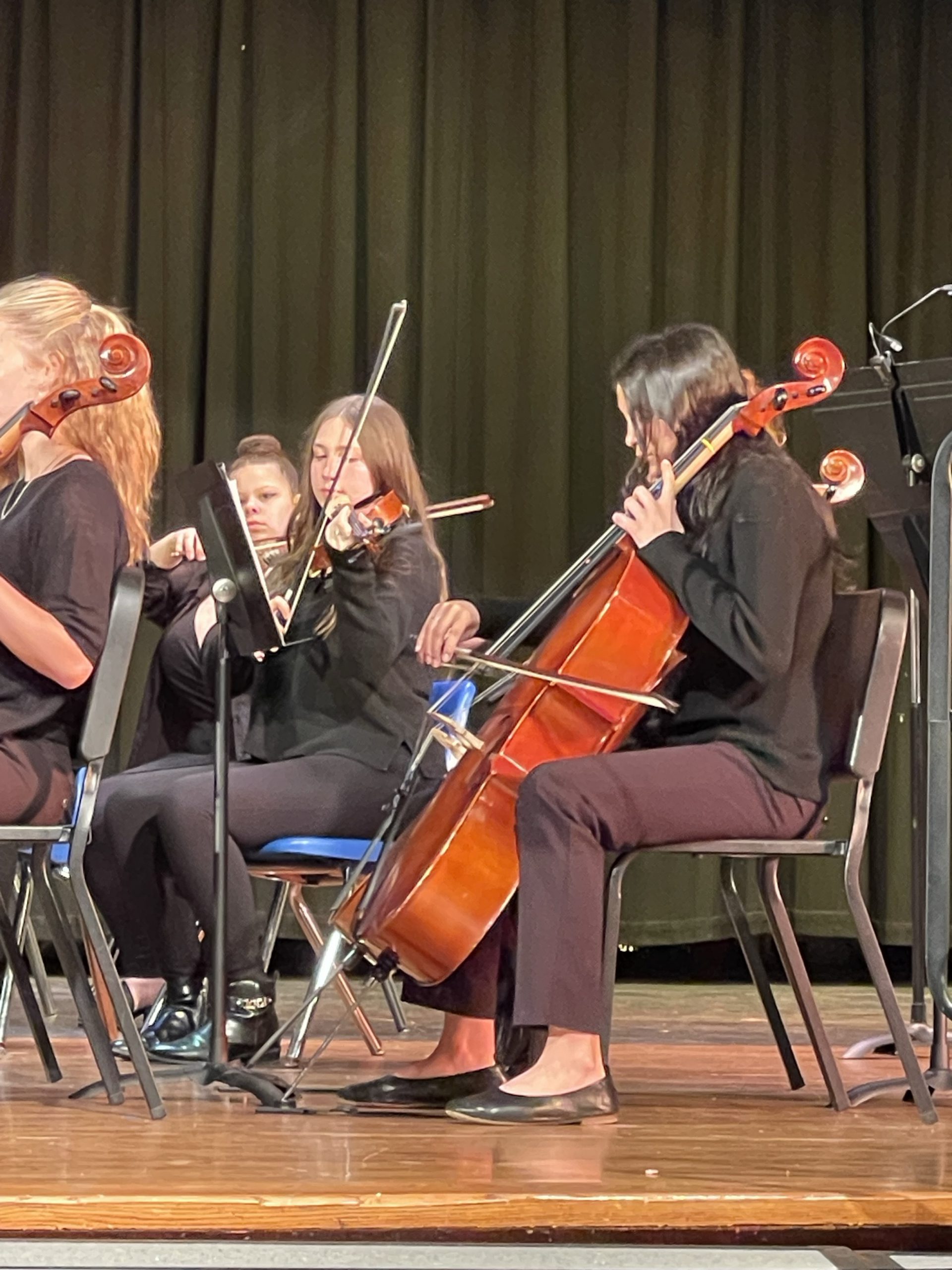 students are playing cello on stage