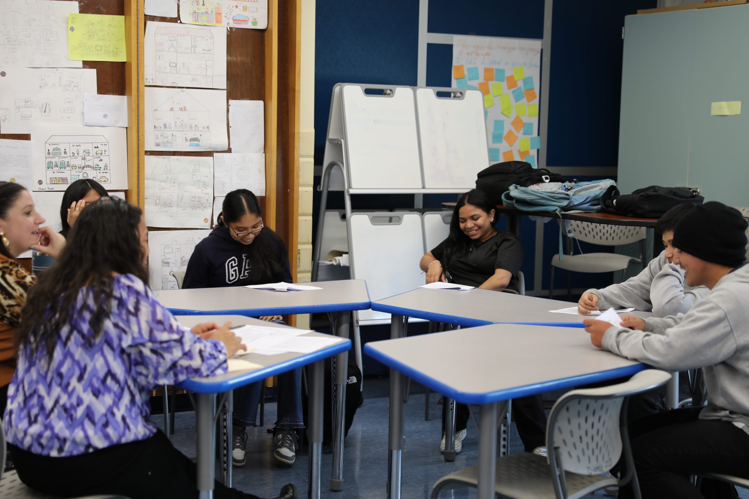 a group of students are engaged in conversation around a table.