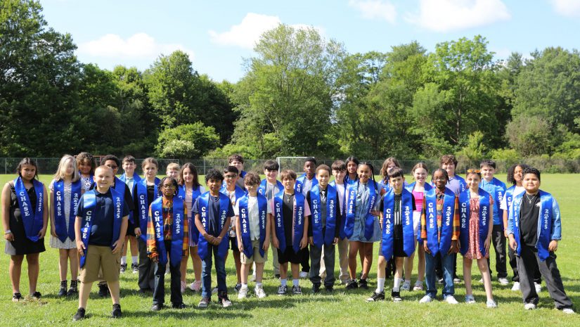 the fifth graders are outside posing.