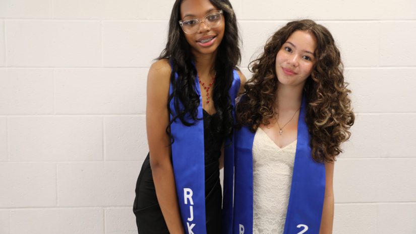 two students in blue sashes are posing